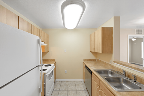 A kitchen with a white refrigerator and wooden cabinets.