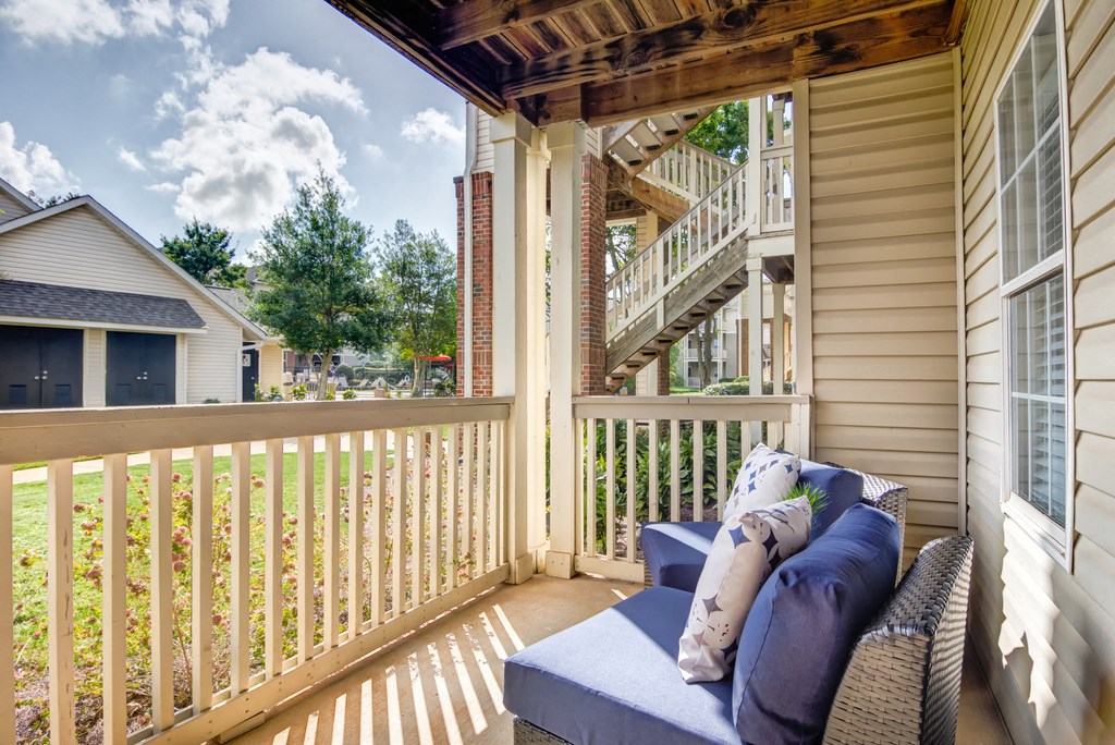Staged patio with two outdoor chairs, over looking native landscaping and pool area.