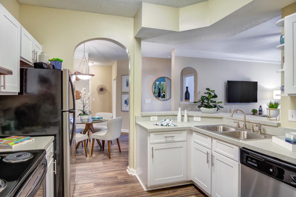 an open kitchen and dining area with stainless steel appliances and white cabinets