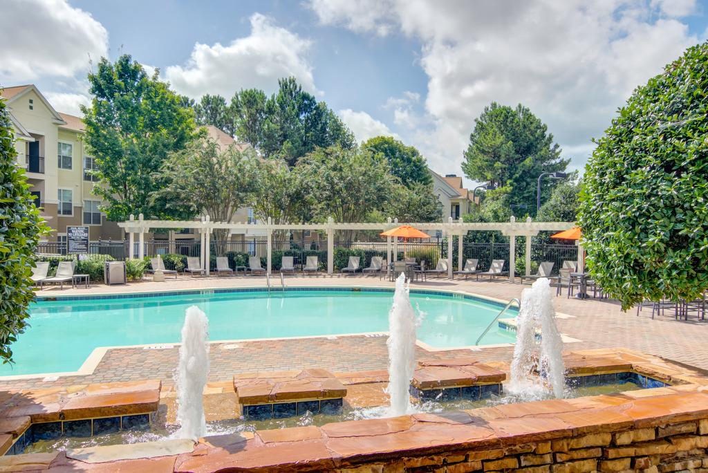 a swimming pool with water fountains   and a building in the background