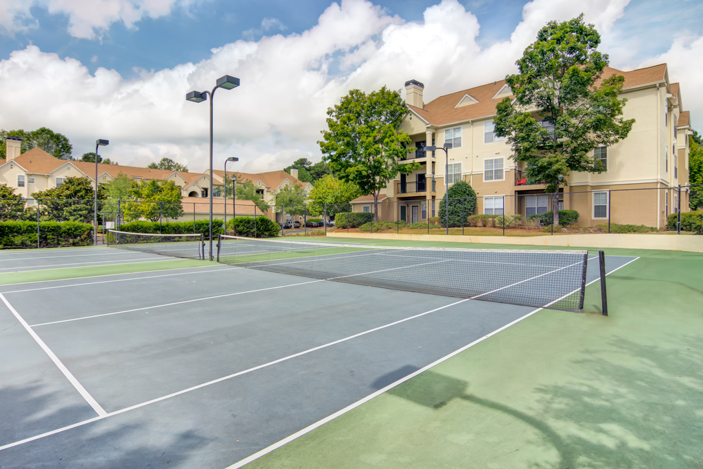 two tennis courts with apartments in the background