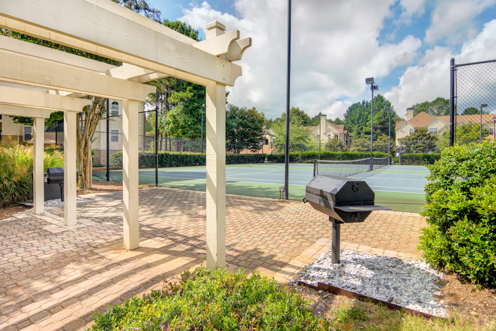 the clubhouse has a tennis court with a grill on the side
