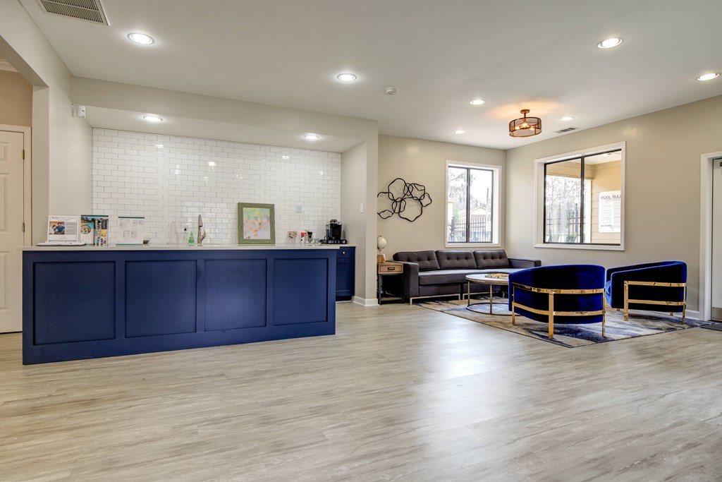 A spacious living room with a dark blue sofa set and a light wooden floor.