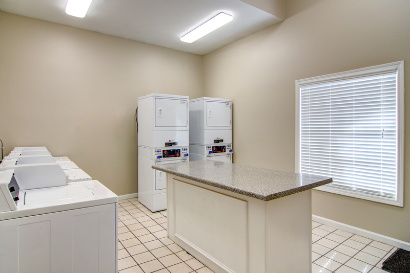 a laundry room with a counter and two washer and dryers and a window