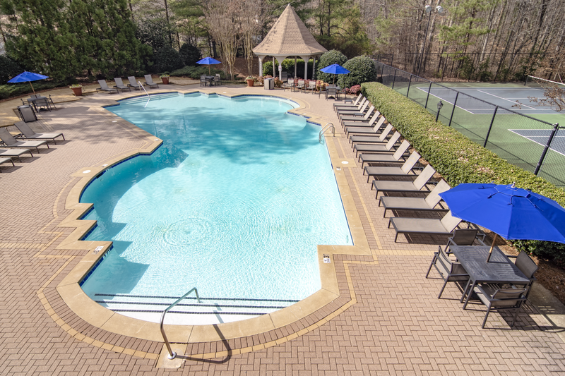 a swimming pool with chairs and umbrellas near a resort pool