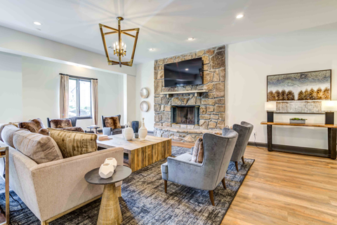 A living room with a stone fireplace and a large painting on the wall.