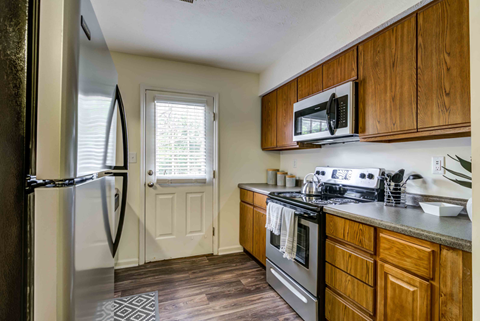 A kitchen with wooden cabinets and a stainless steel refrigerator.