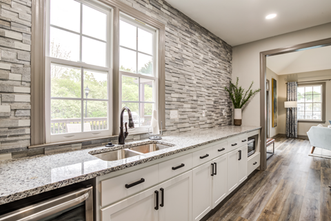 a kitchen with white cabinets and a sink and a large window