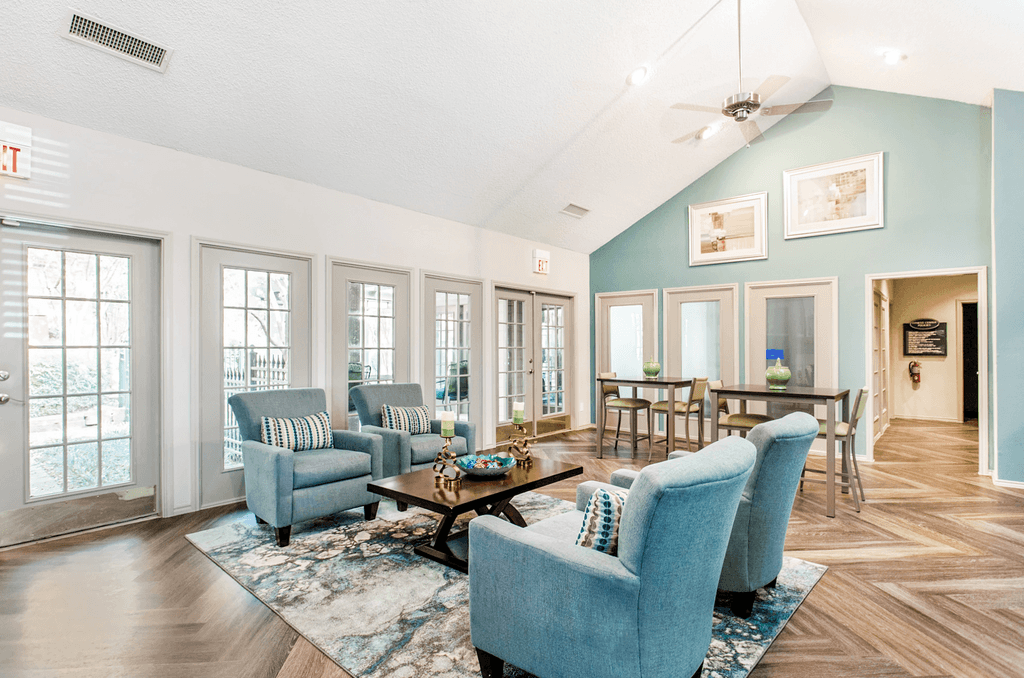 Clubhouse interior with upholstered chairs, accent rug, coffee table, high top tables and chairs, vaulted ceiling and ceiling fan