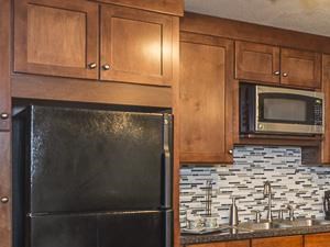 Clubhouse Kitchen with Breakfast Bar Brown Cabinets and Black Appliances