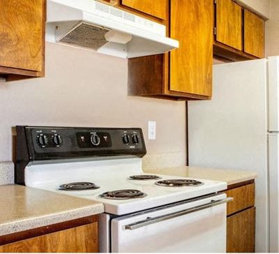 Kitchen with stove and refrigerator. Cabinets above all the appliances.