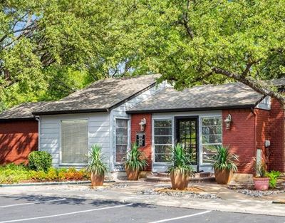Front office exterior with parking lot, sidewalks, grass areas, flowers, bushes.