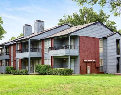 Exterior of apartment with a grass area and bushes by the building