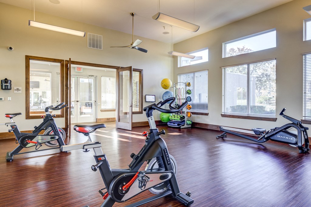 a gym with treadmills and exercise equipment in a room with windows