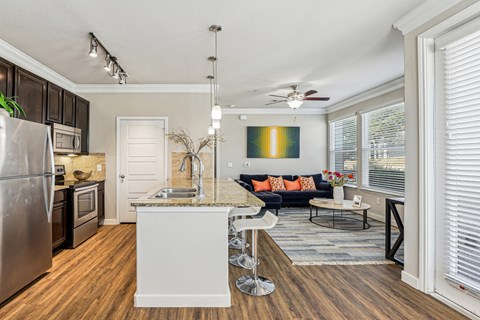 A modern kitchen with a refrigerator, sink, and a dining area with a couch and chairs.