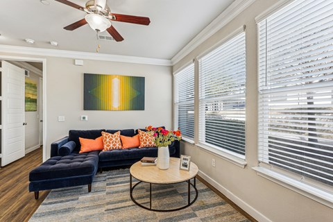 A living room with a blue couch and a painting on the wall.