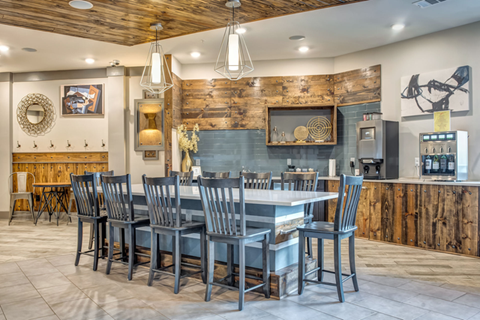 A kitchen with a wooden wall and a large island with chairs around it.