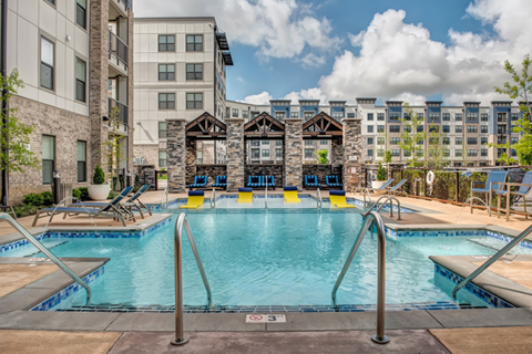 A large outdoor swimming pool with a diving board and lounge chairs.