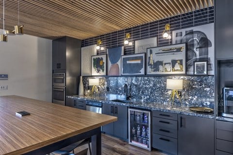 A modern kitchen with a wooden table and black cabinets.
