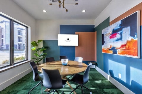 A conference room with a table, chairs, and a painting on the wall.