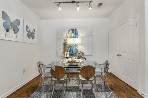 A dining room with a table set for four and a painting of a butterfly on the wall.