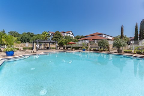 A large swimming pool in a backyard with a fence and a house in the background.