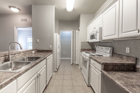 A kitchen with white cabinets and granite countertops.