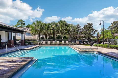 A large swimming pool with a wooden deck and a fence surrounding it.
