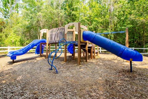 A playground with a blue slide and a wooden structure.