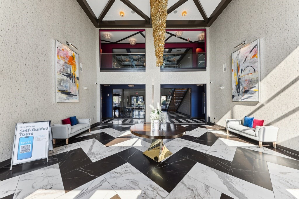 A lobby with a black and white marble floor and a sign offering self-guided tours.