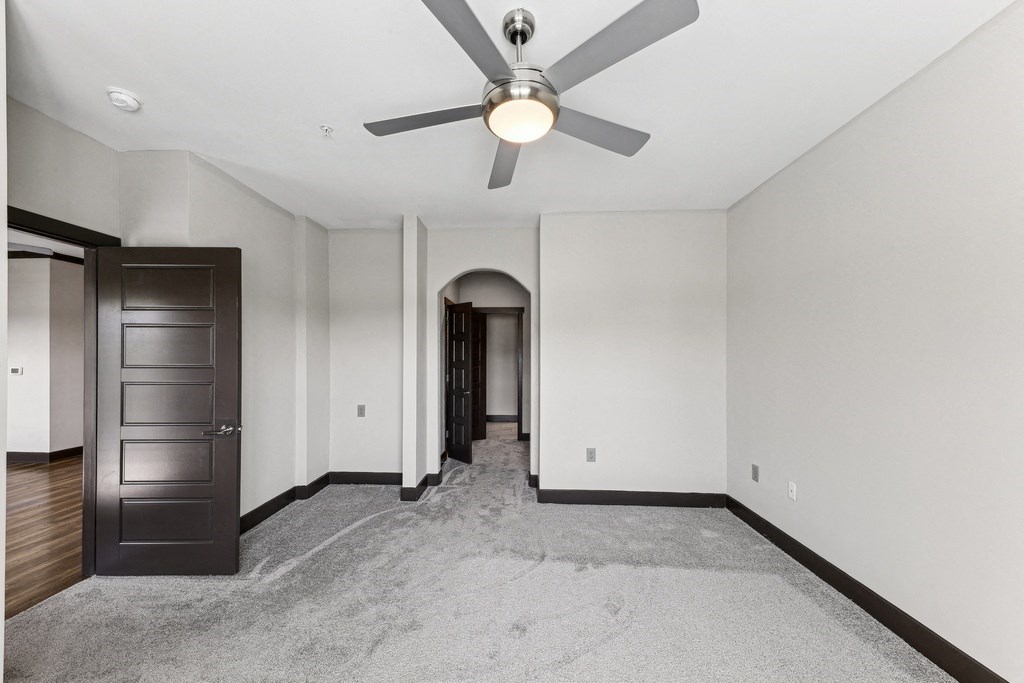 A room with a ceiling fan and a carpeted floor.
