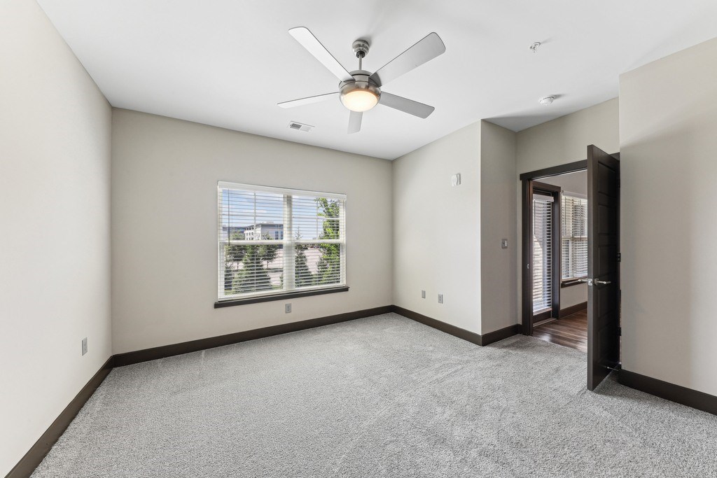 A room with a ceiling fan and carpeted floor.