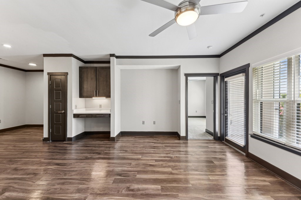 A room with a ceiling fan and wooden flooring.