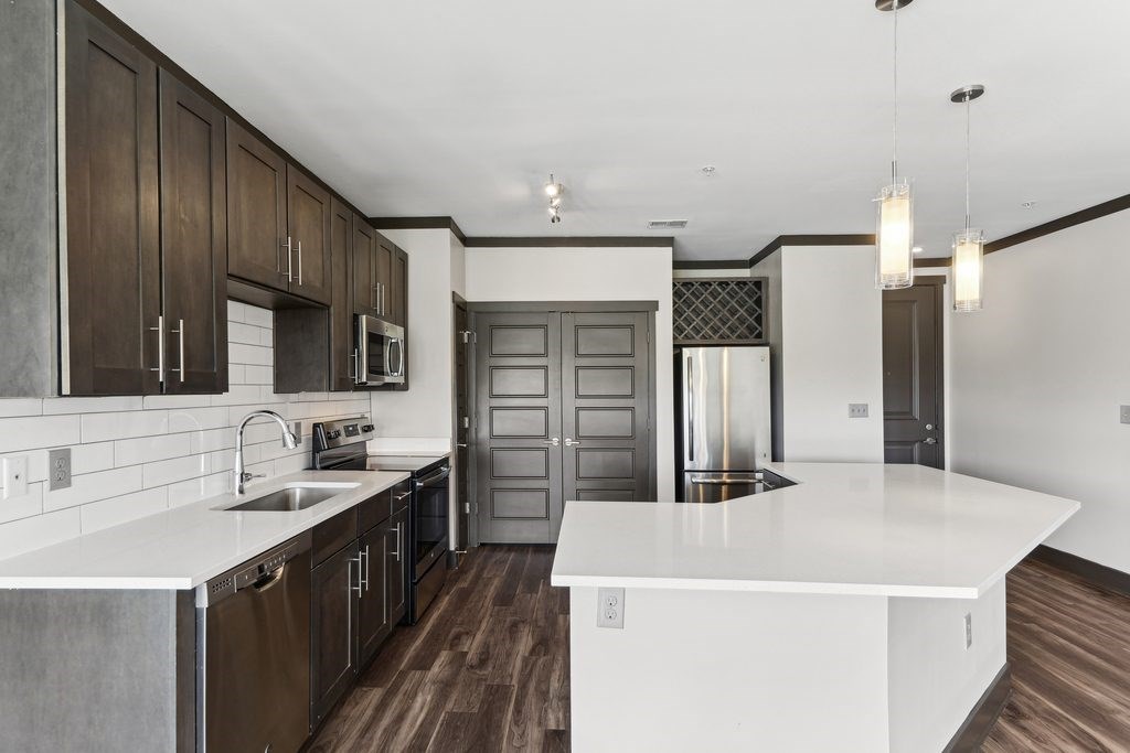 A modern kitchen with dark wood cabinets and a white countertop.