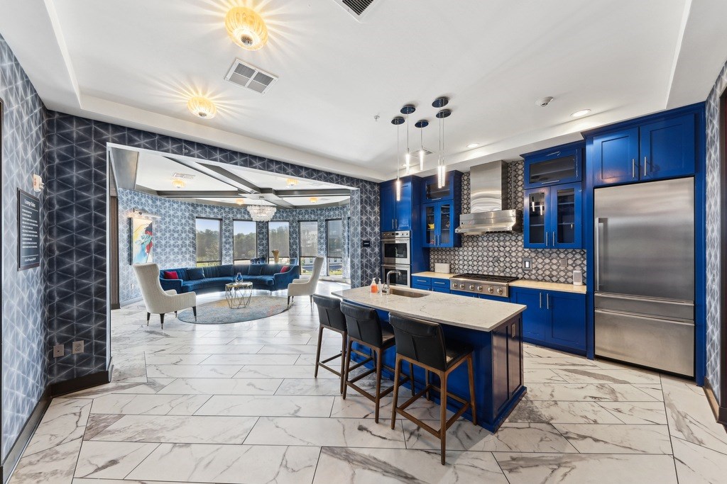 A kitchen with blue cabinets and a marble floor.