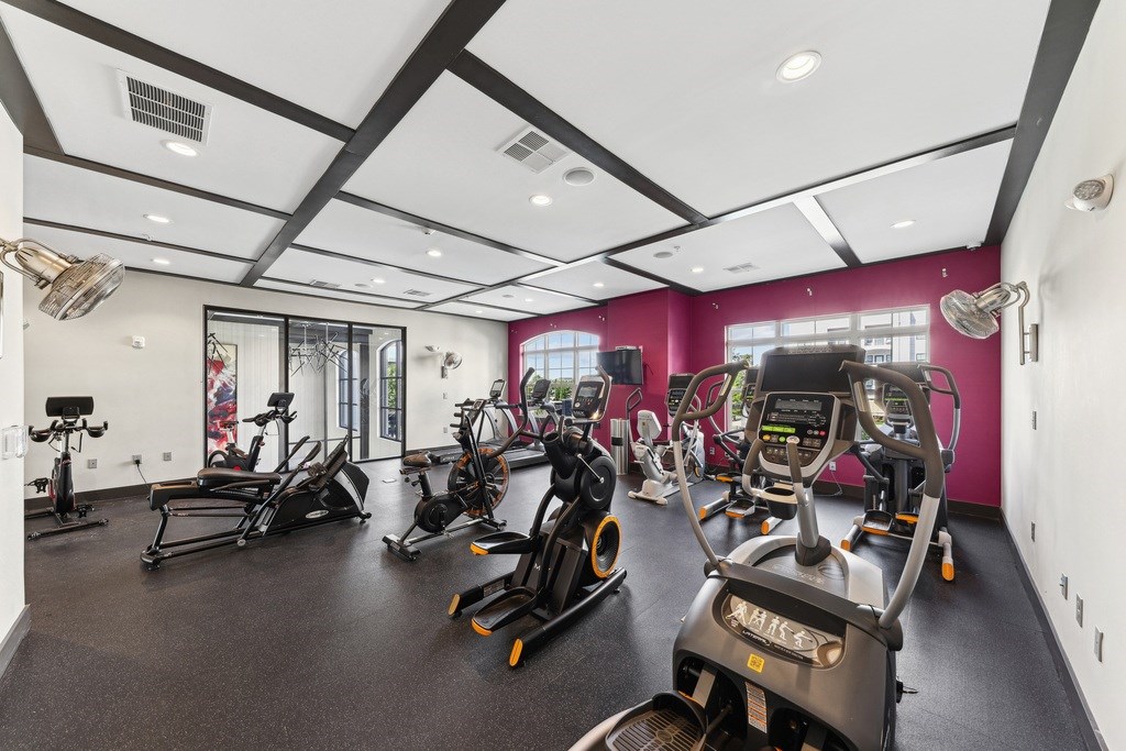 A gym with a row of treadmills and elliptical machines.