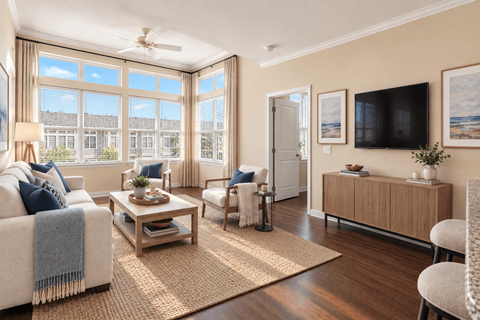 A living room with a large window, a sofa, a coffee table, and a television.