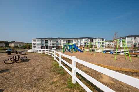 A playground with a white fence and a green slide.