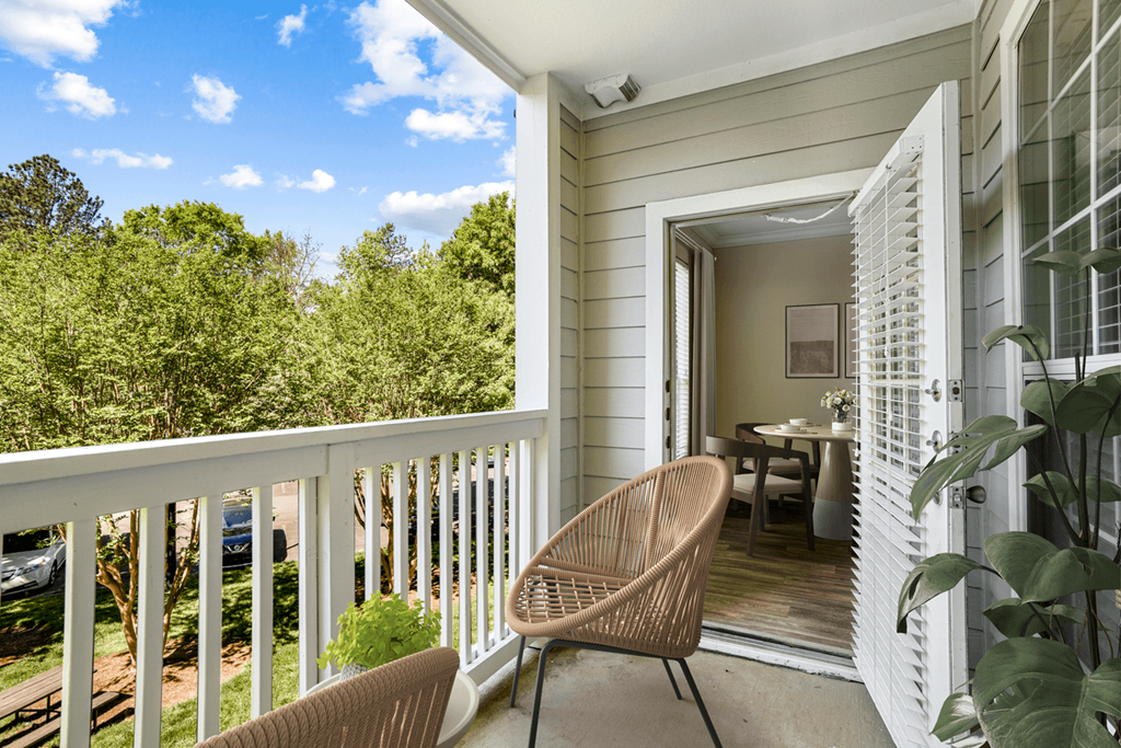 a balcony with a wicker chair and a door leading to a dining area