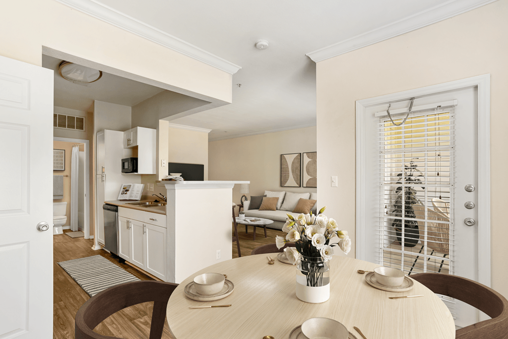 a dining area with a table and chairs and a kitchen in the background