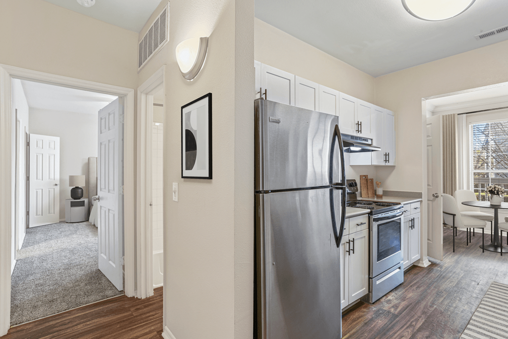 a kitchen with white cabinetry and a stainless steel refrigerator