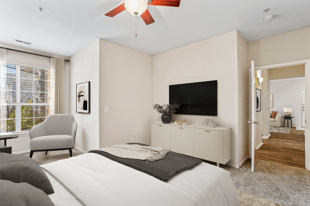 a bedroom with a large window and a ceiling fan