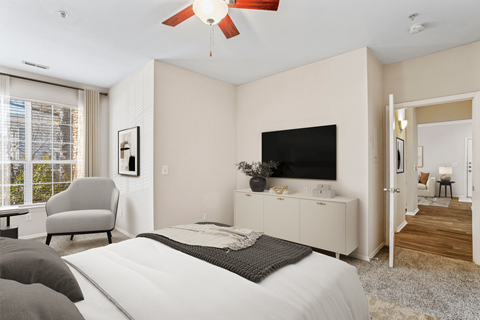 a bedroom with a large window and a ceiling fan