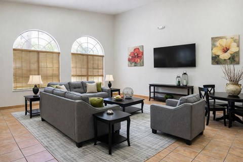 A living room with a grey couch, a black coffee table, and a flat screen TV mounted on the wall.