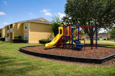 A playground with a yellow slide and red and blue swings.
