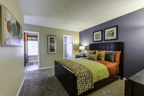 Carpeted bedroom with doorways leading to the closet, bathroom and living room.