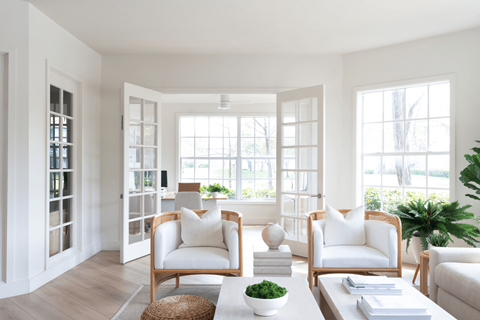 A living room with white furniture and a large window.