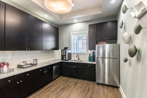 a kitchen with black cabinets and a stainless steel refrigerator