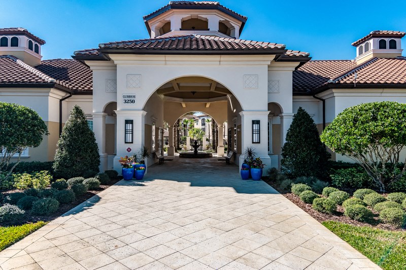 a large mansion with a walkway with potted plants