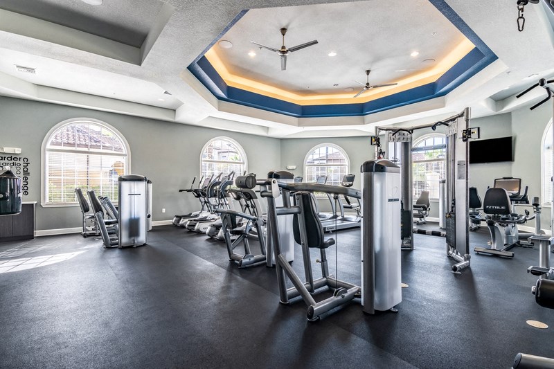 a gym with cardio machines and chairs and windows